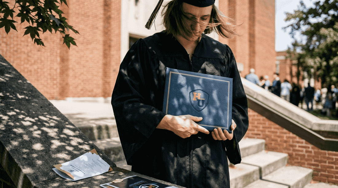 Graduate holding diploma cover outside auditorium